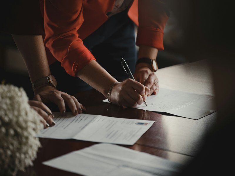 A couple thoughtfully signing a wedding venue contract, a symbol of their commitment to smart budgeting for their special day.
